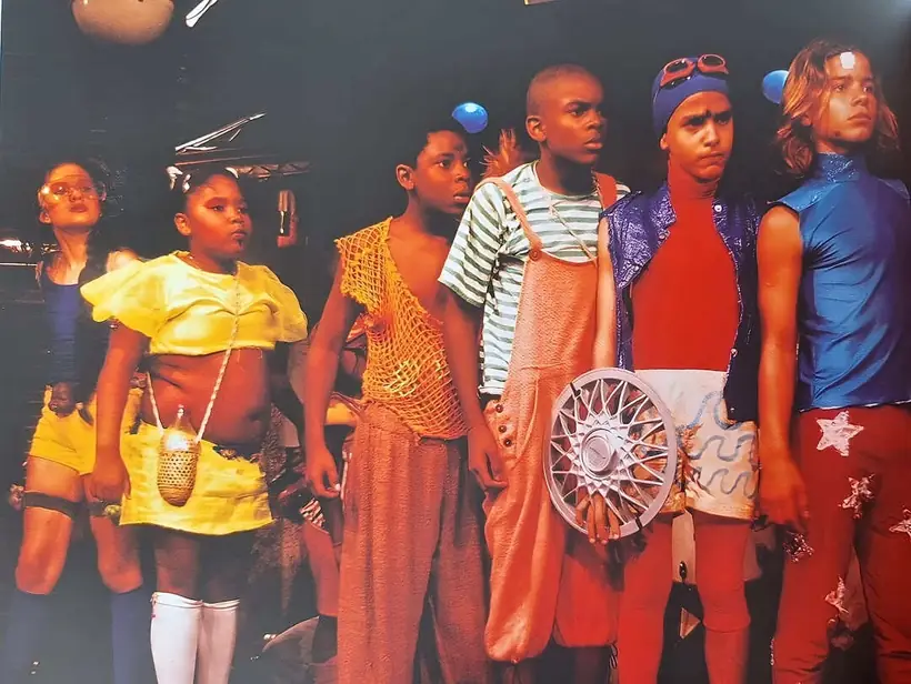 Crianças em figurinos coloridos posando juntas ao final de uma apresentação