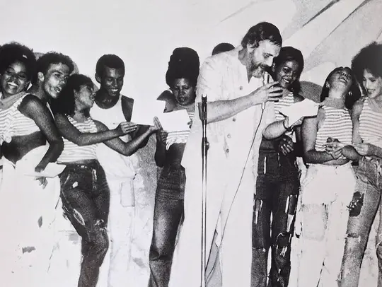Fotografia de arquivo em preto e branco: grupo de jovens reunido em torno de um microfone